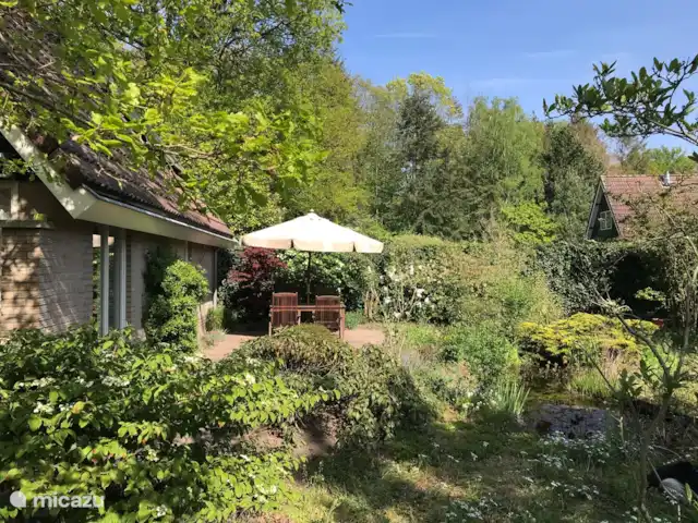 De mooi sfeervolle tuin bevat veel groen, privacy en een vijver